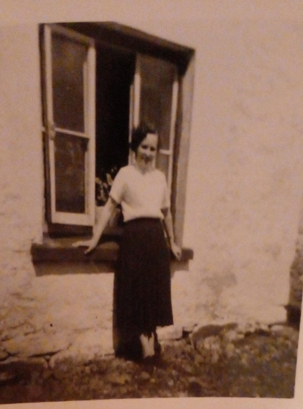 Tillie Craig at some time in the 1950`s. According to local folklore, this house had a small shop incorporated in the building and this is why the window behind Tillie is unusually large for this house.